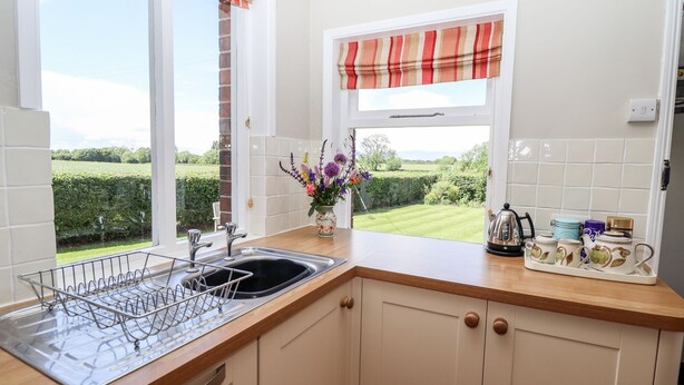A kitchen with a window, a sink, and a dish rack. - East Farm Cottage (Lincoln)