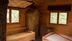 Eine Hütte mit zwei Einzelbetten, einem Holzstuhl und einem kleinen Tisch.