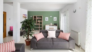 A living room with a grey sofa, a green wall, a bookshelf, and a potted plant. - Villa Papillon – lovingly furnished & superbly equipped vacation oasis with pool (Pula)