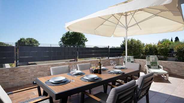 An outdoor dining area with a table set for four, surrounded by chairs, under a large umbrella. - Villa Papillon – lovingly furnished & superbly equipped vacation oasis with pool (Pula)