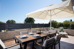 An outdoor dining area with a table set for four, surrounded by chairs, under a large umbrella. - Villa Papillon – lovingly furnished & superbly equipped vacation oasis with pool (Pula)