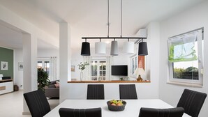 A modern dining area with a white table, black chairs, and a central hanging light fixture. - Villa Papillon – lovingly furnished & superbly equipped vacation oasis with pool (Pula)