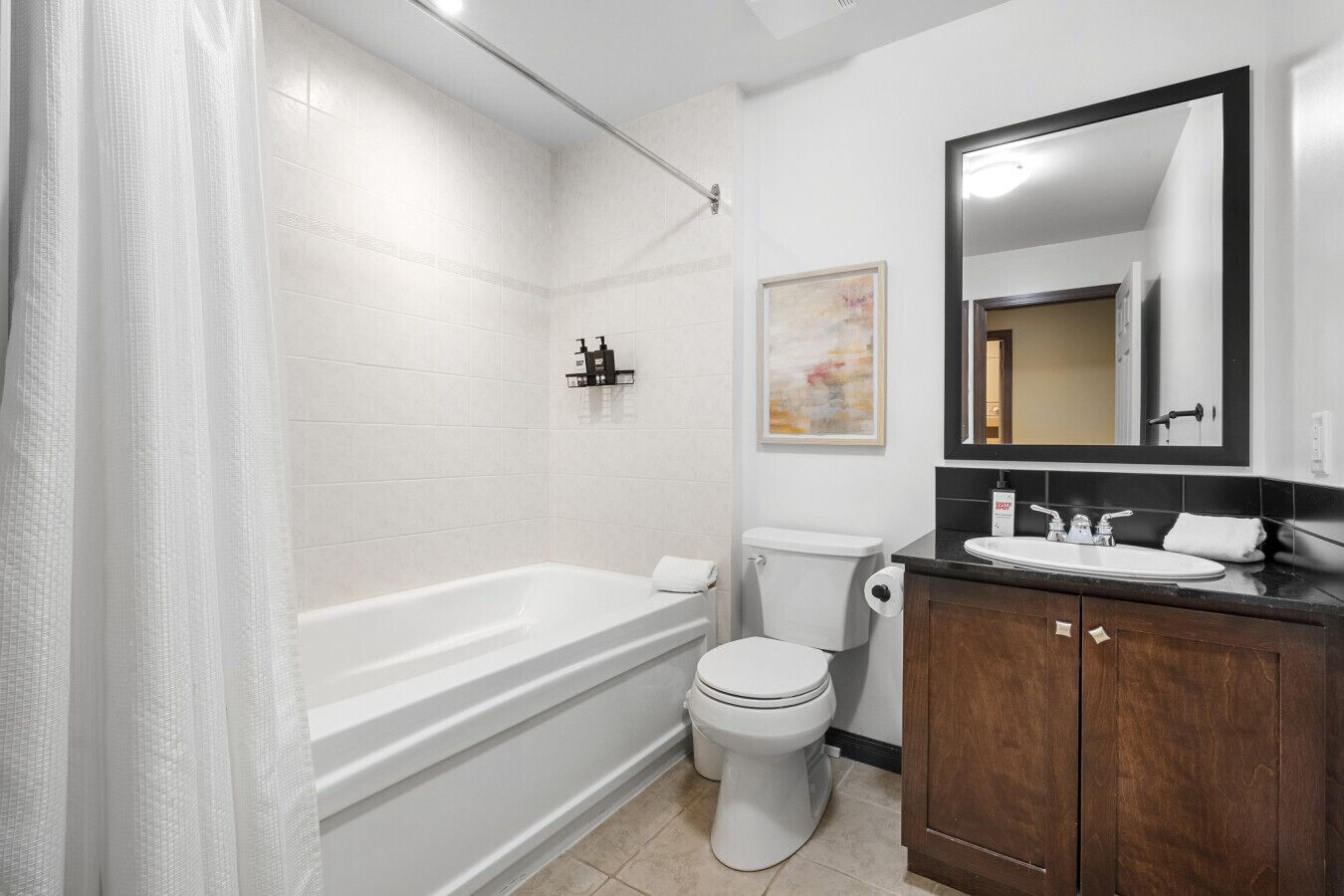 A bathroom with a bathtub, toilet, and vanity with a mirror.