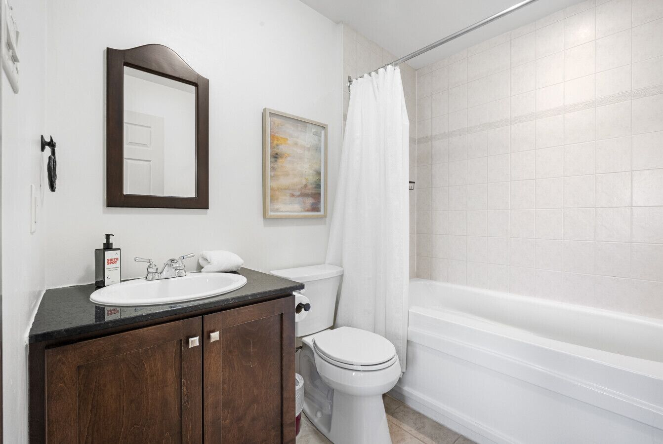Un baño con lavamanos blanco, espejo, inodoro y bañera.