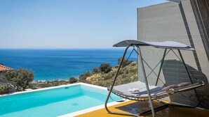 Una piscina con una silla hamaca y vistas al océano.