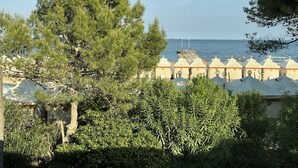 Ein Hotel an der Küste mit einer Reihe weißer Zelte, einer großen Kiefer und Blick auf das Meer.
