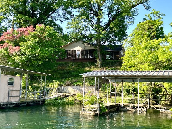 A lakeside house with a dock and a covered area.