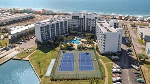 Un hôtel situé sur la côte, composé de plusieurs bâtiments, doté d’un court de tennis et d’une piscine.