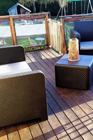 A wooden deck with wicker furniture and a wicker lamp.