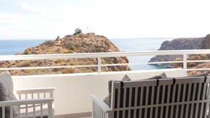 Un balcon avec vue sur une côte rocheuse et l’océan.