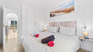 A hotel room with a large bed, a painting on the wall, and a view through an open door. - Nice Apartment in a Wonderful Area with Shared Pool & Wi-Fi (Las Ramblas)