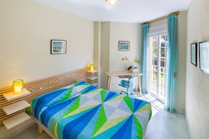 A bedroom with a bed, bedside tables, a desk, and a window with curtains.