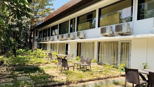 Un edificio con varios balcones, mobiliario exterior y un jardín.