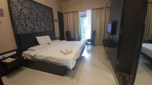 Habitación de hotel con una cama grande, televisión y vistas al exterior.
