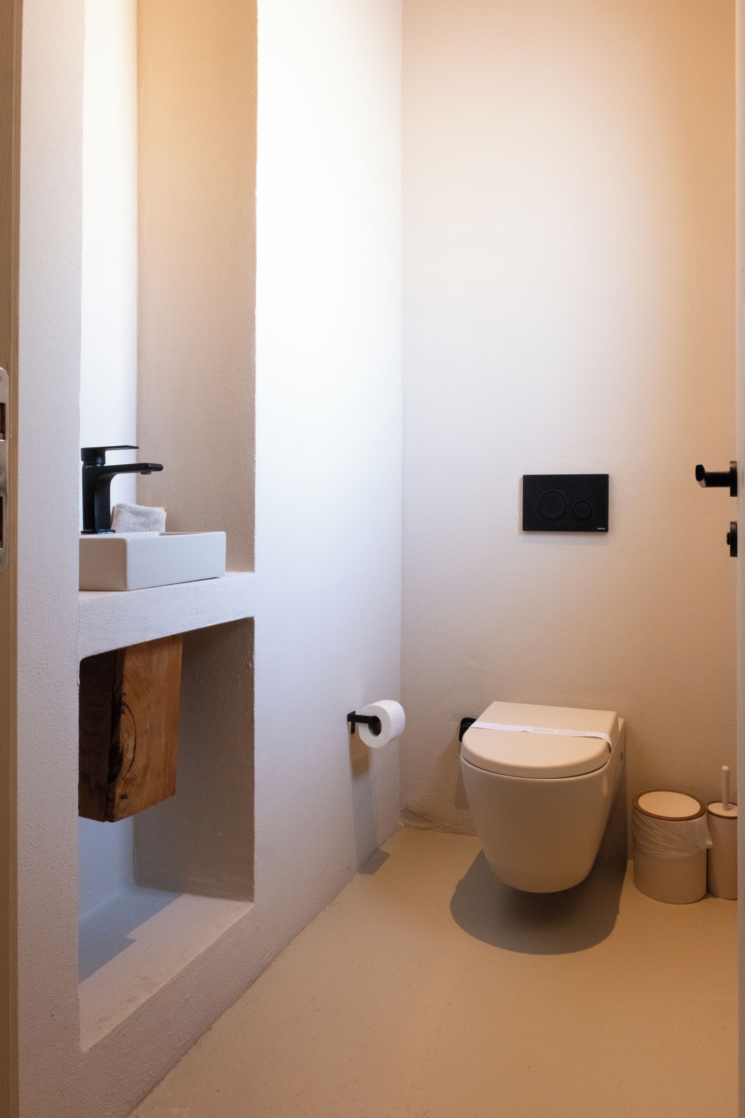 A small, modern bathroom with a toilet, sink, and a towel rack.