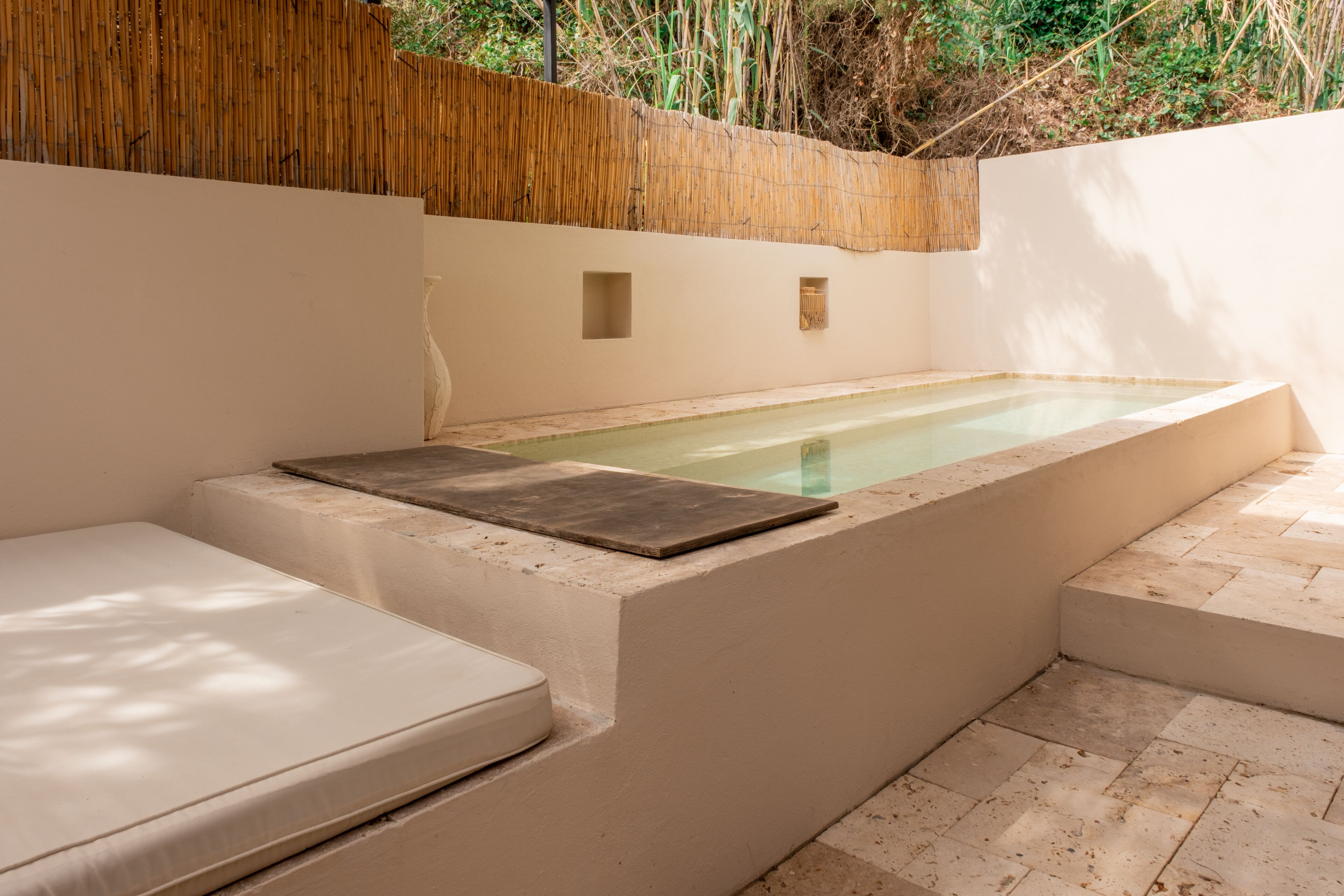 A spa area with a hot tub, seating, and a bamboo wall.