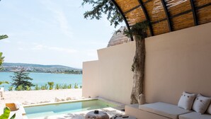 A pool area with a sofa and stools, a view of the sea, and a tree. - Gaia By The Sea - Adult Only (Çesme)
