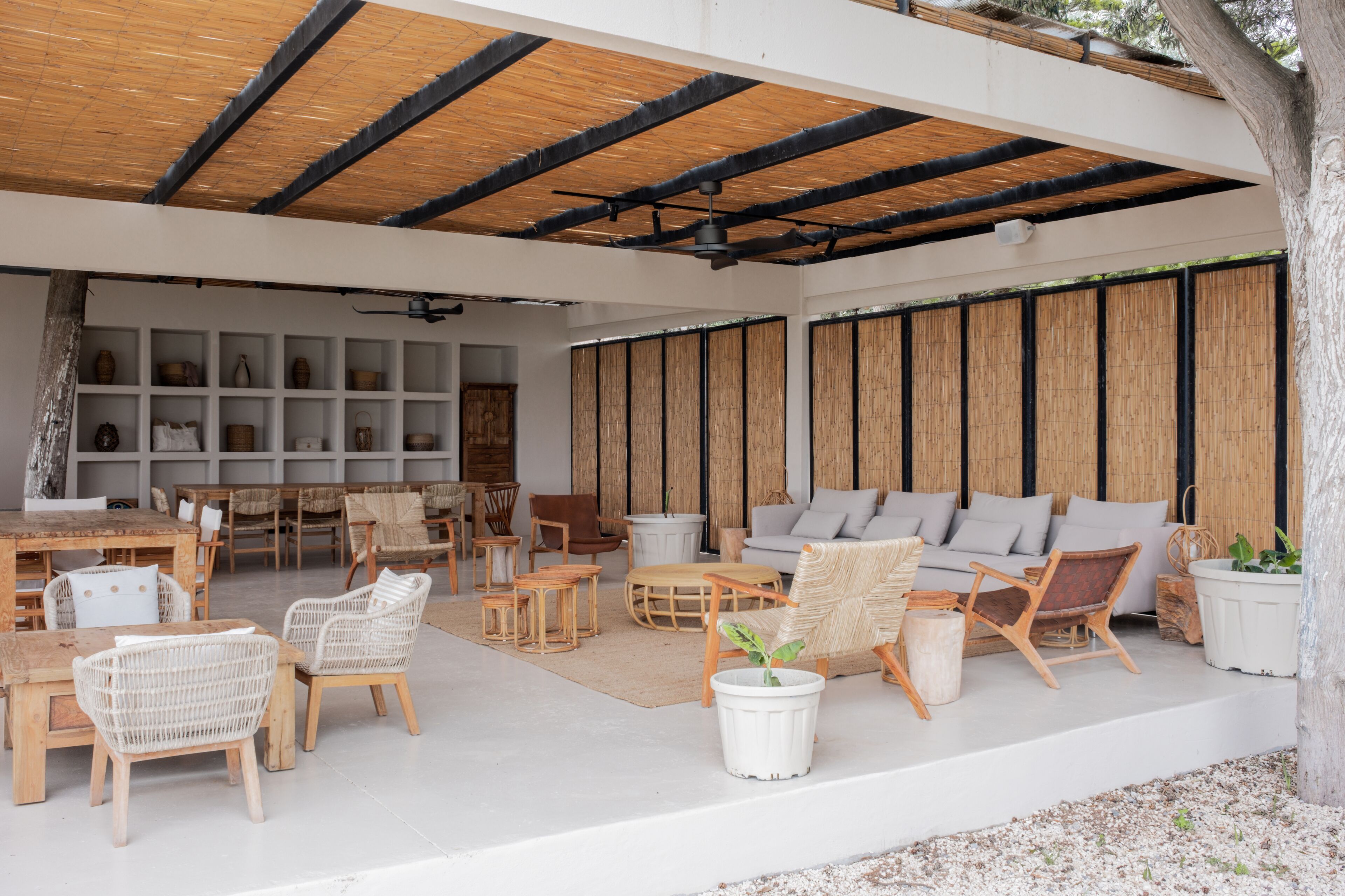Un espacio de estar al aire libre cubierto con muebles de mimbre, una mesa blanca y una planta en maceta.