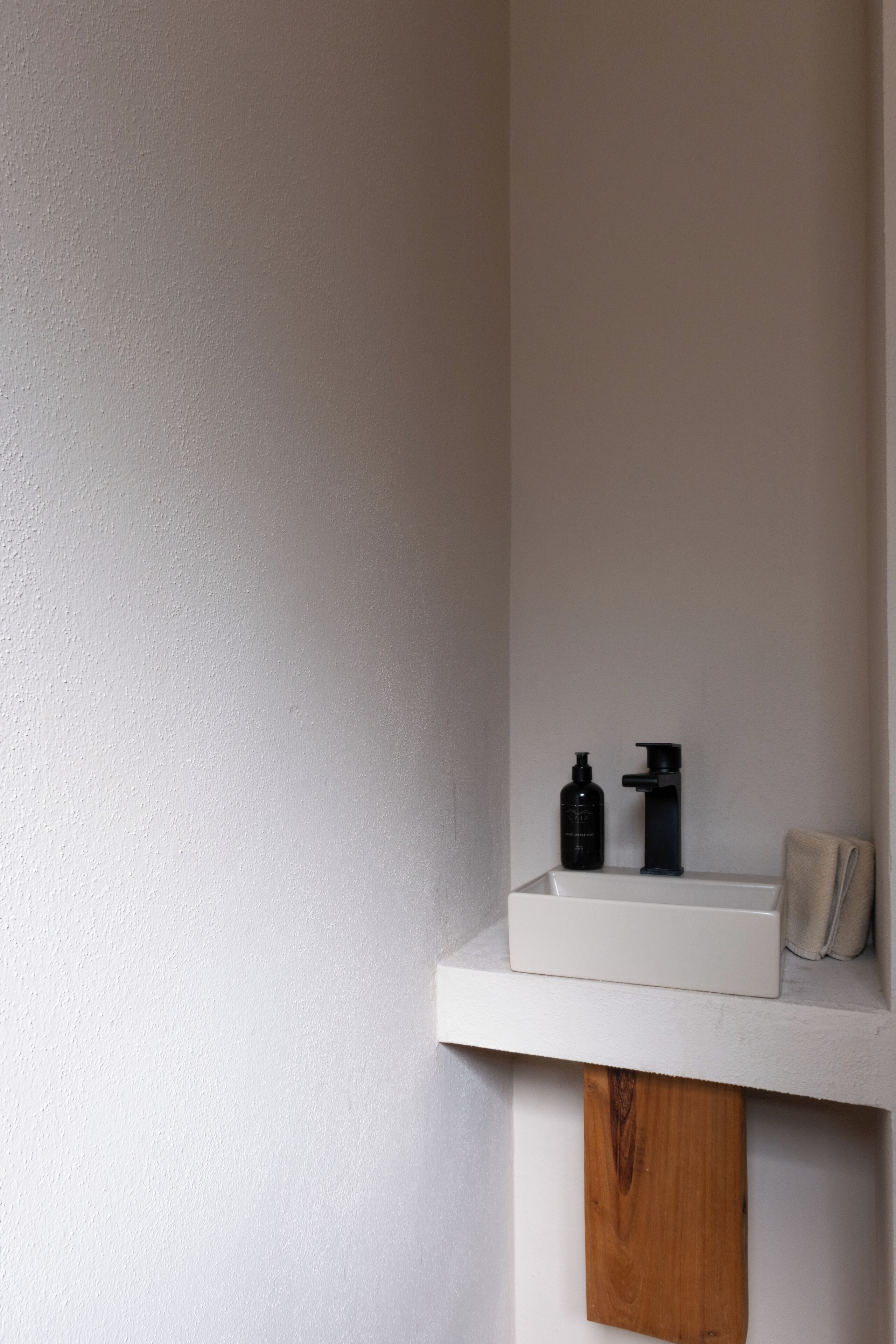 A white shelf with a black bottle and a pump dispenser.