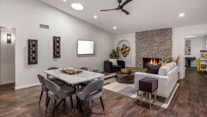 Un salon moderne comprenant un coin repas, une cheminée et un ventilateur de plafond.