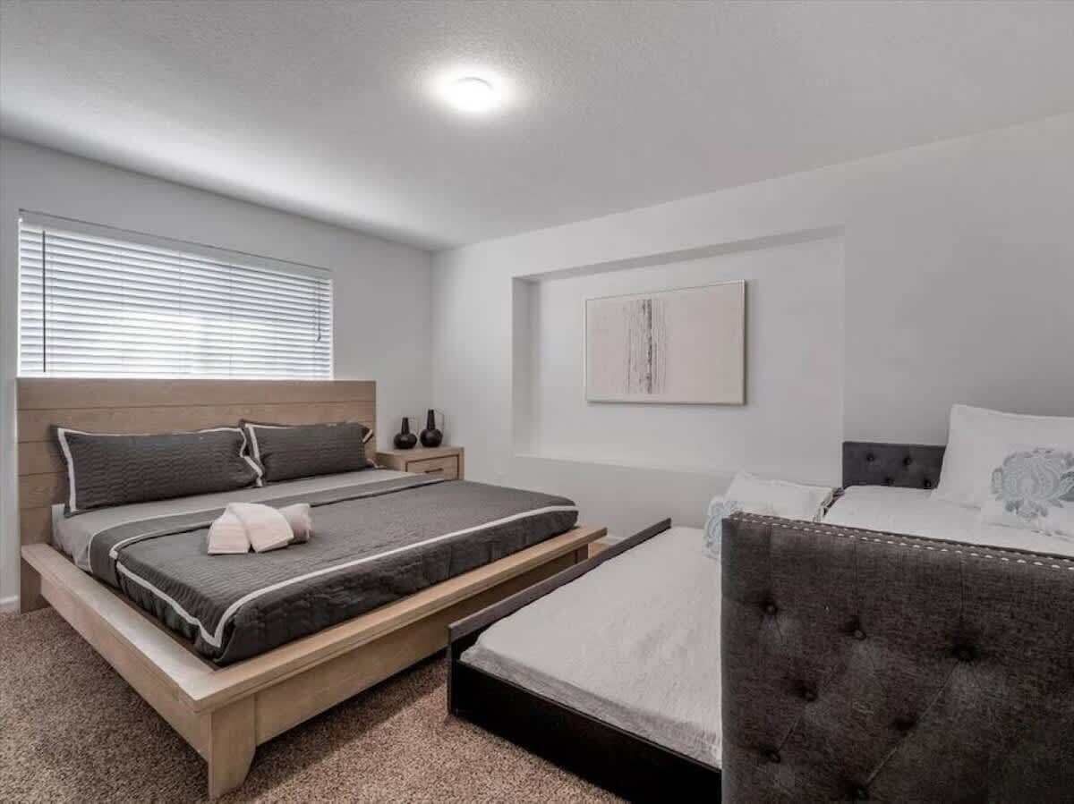 Ein Schlafzimmer mit einem Bett, einem Nachttisch, einer Fensterbank und einem Wandbild.