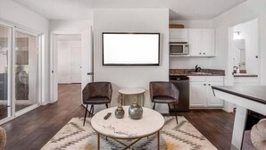 Une cuisine moderne avec des meubles blancs, un four à micro-ondes encastré et un coin repas comprenant une table ronde et deux chaises.