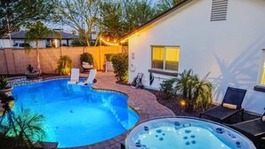 Un jardin avec une piscine, un jacuzzi et un espace salon extérieur.