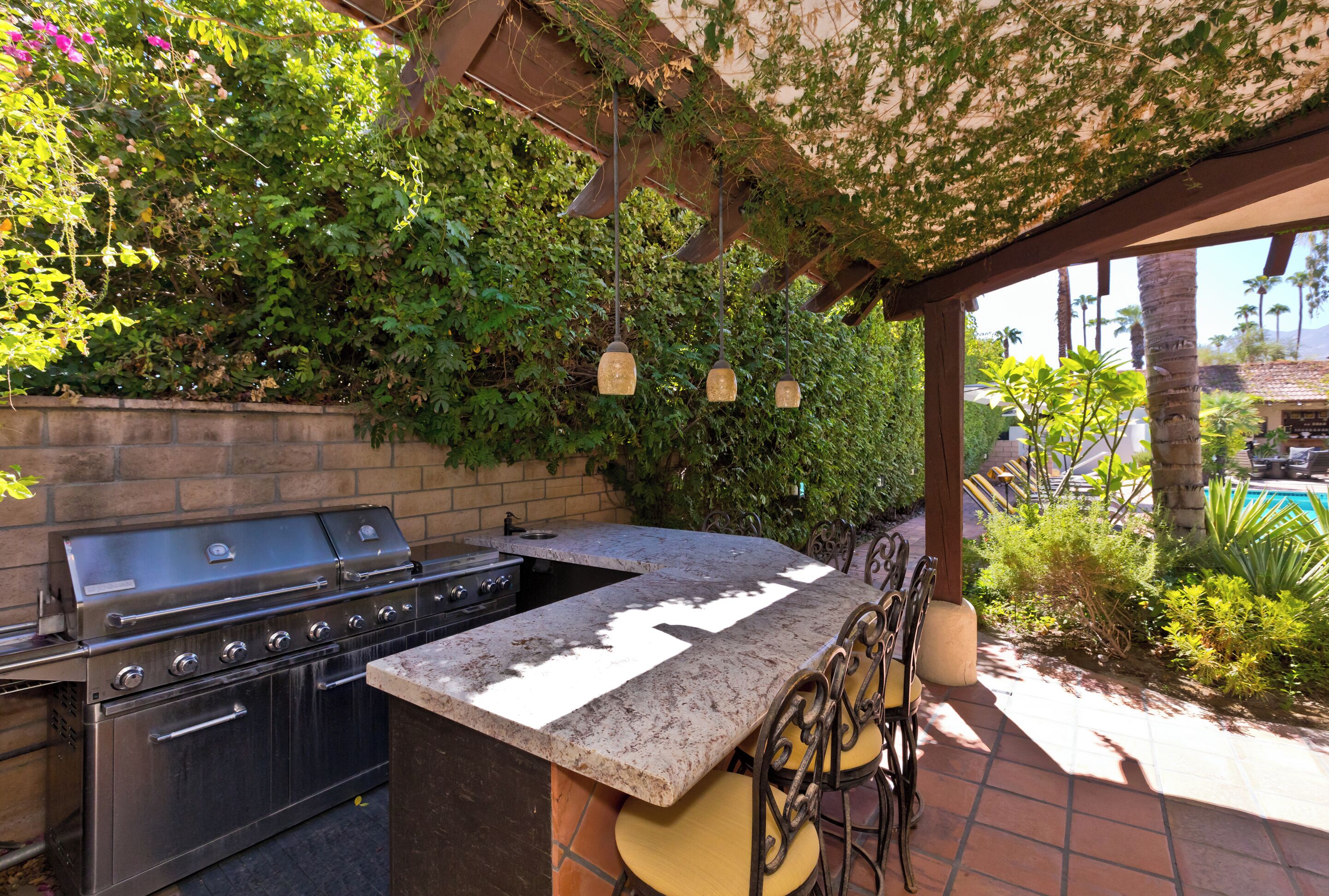 An outdoor kitchen with a grill, bar area, and seating.