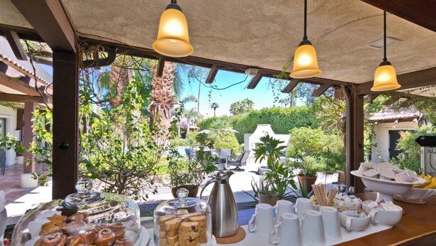 A breakfast buffet with pastries and coffee, set against a backdrop of lush greenery and a clear sky. - LaMaison Palm Springs (Palm Springs)