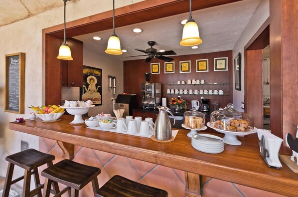 A bar area with a wooden counter, hanging lights, and various food and drink items.