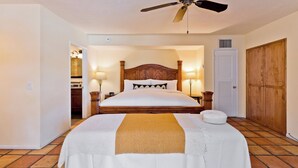 A neatly made bed with a wooden headboard, two bedside lamps, and a ceiling fan. - LaMaison Palm Springs (Palm Springs)