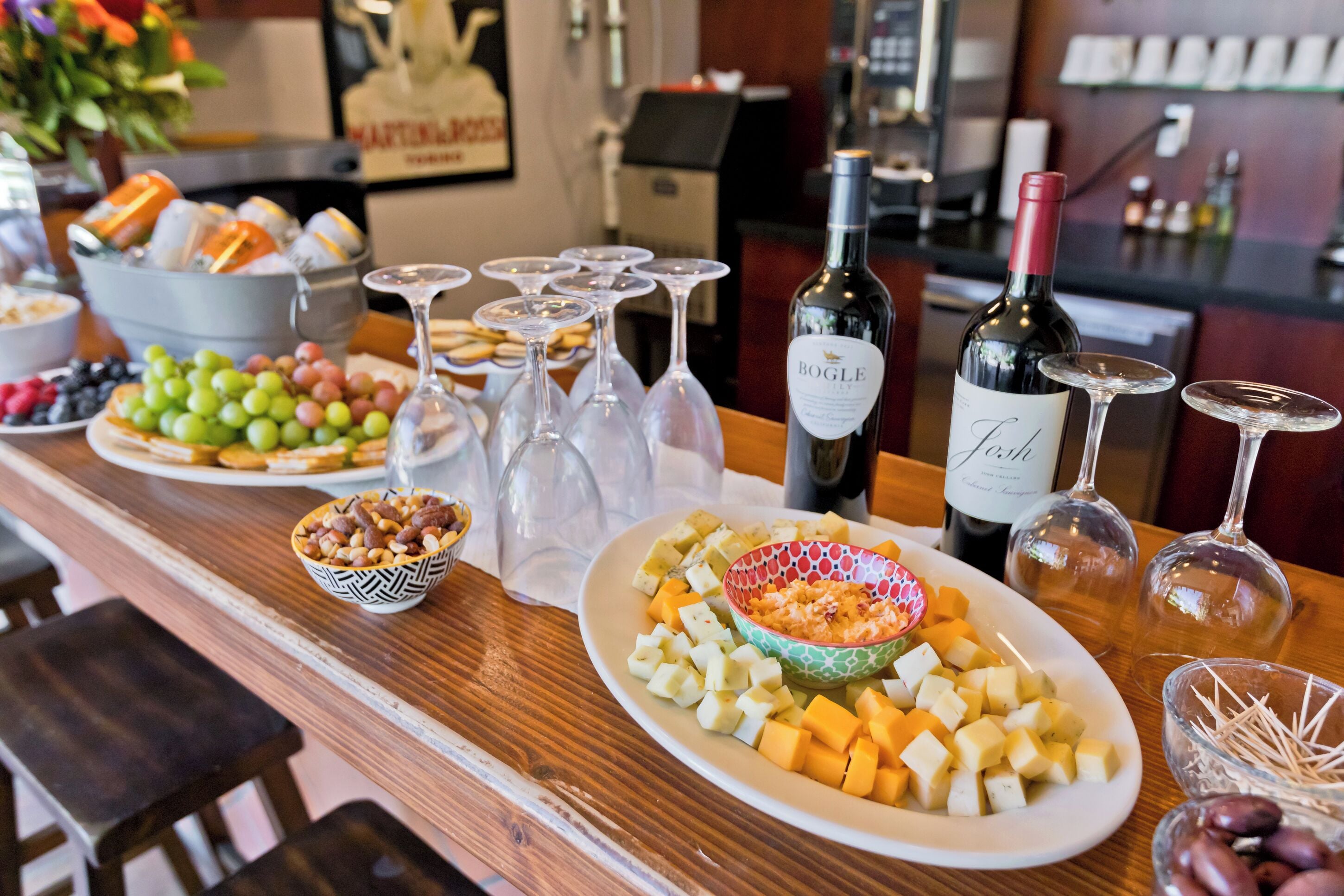 Zona de bar con diferentes bandejas de comida, copas de vino y botellas.