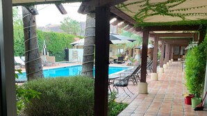 A covered patio area with a pool, outdoor seating, and potted plants. - LaMaison Palm Springs (Palm Springs)
