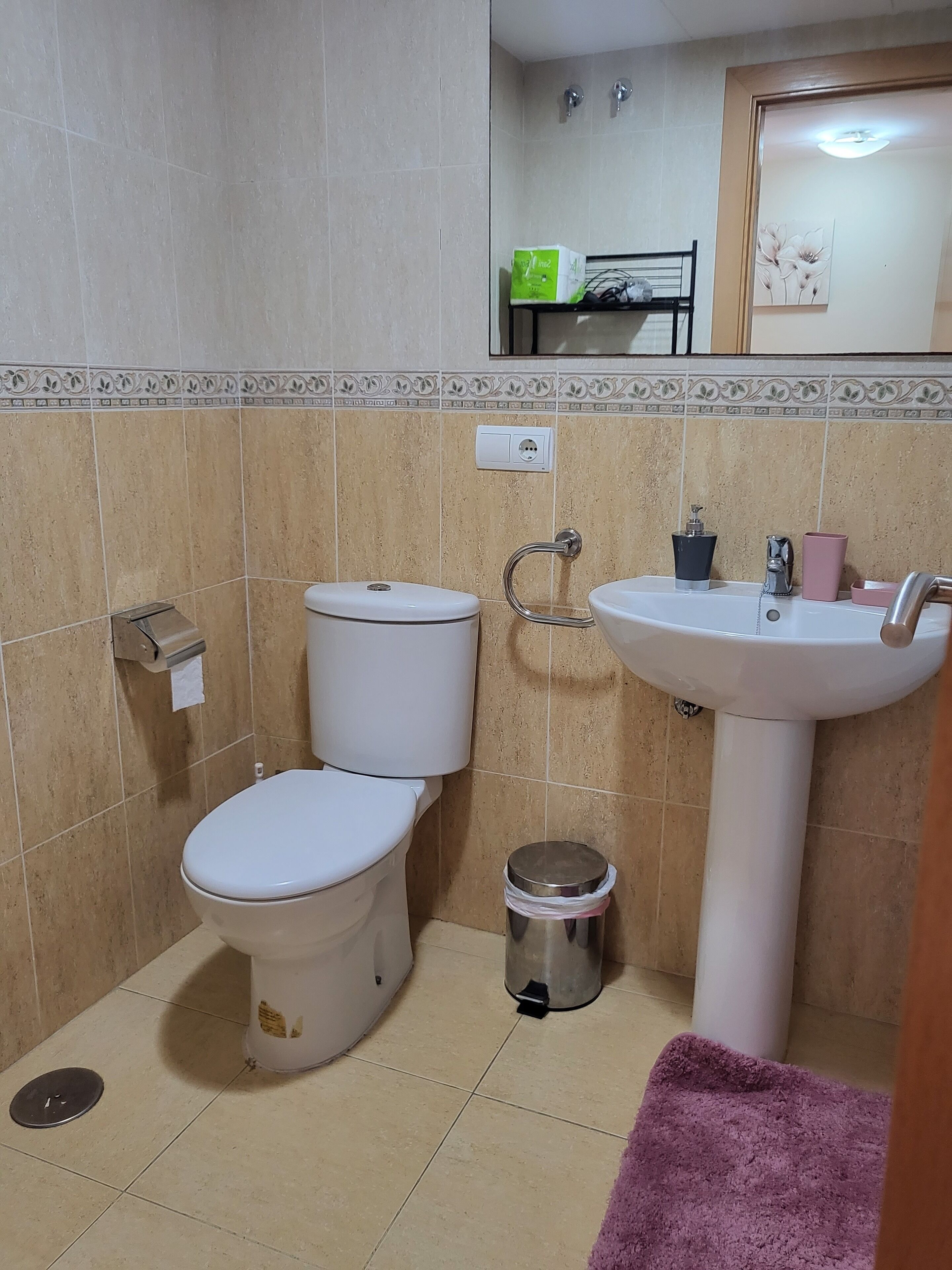 A bathroom with a toilet, sink, and trash can.