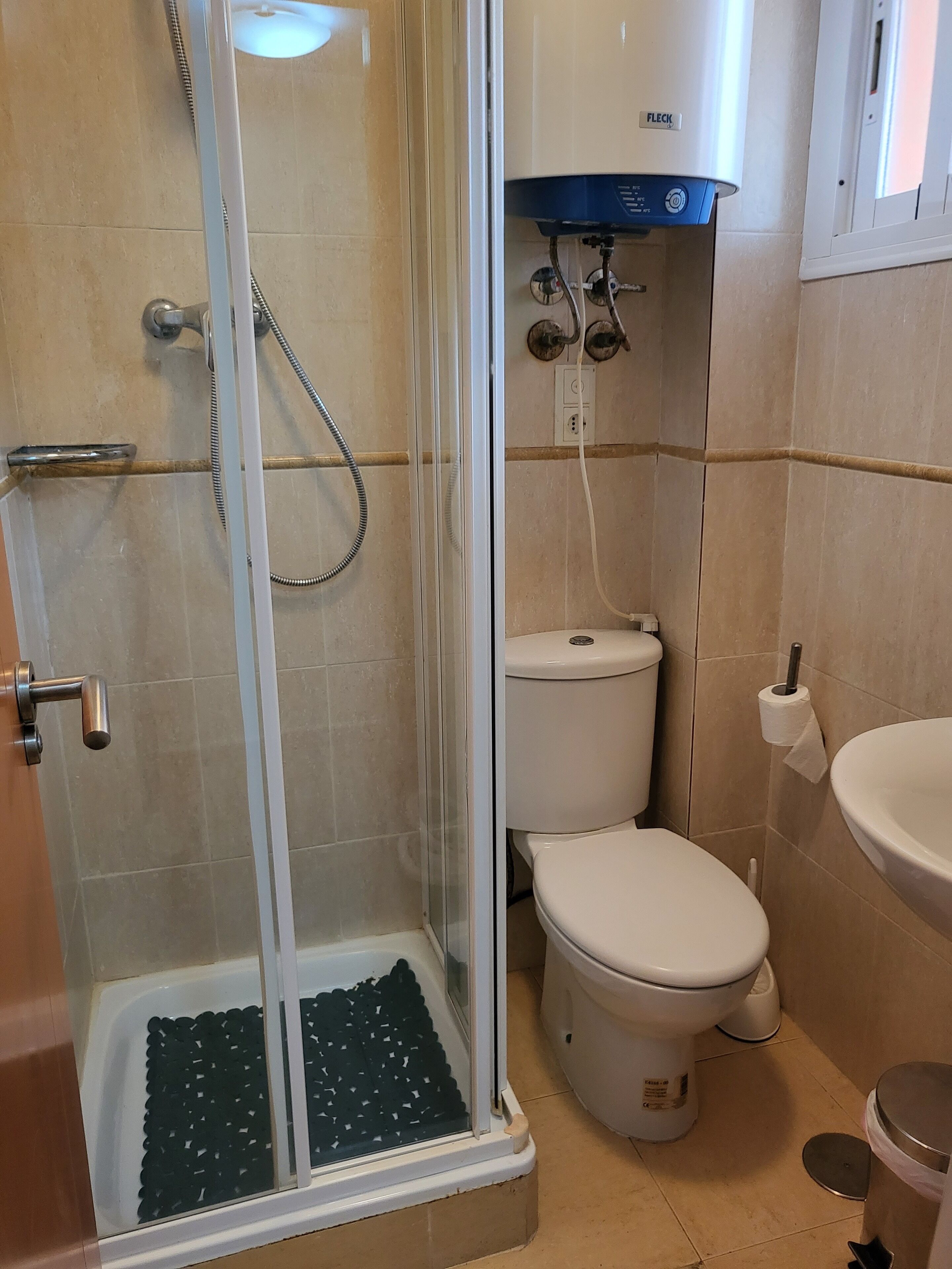 Un baño con ducha de vidrio, inodoro y lavamanos.