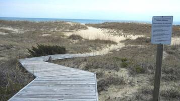 A wooden boardwalk leading to a beach with a sign indicating it is a nature reserve.