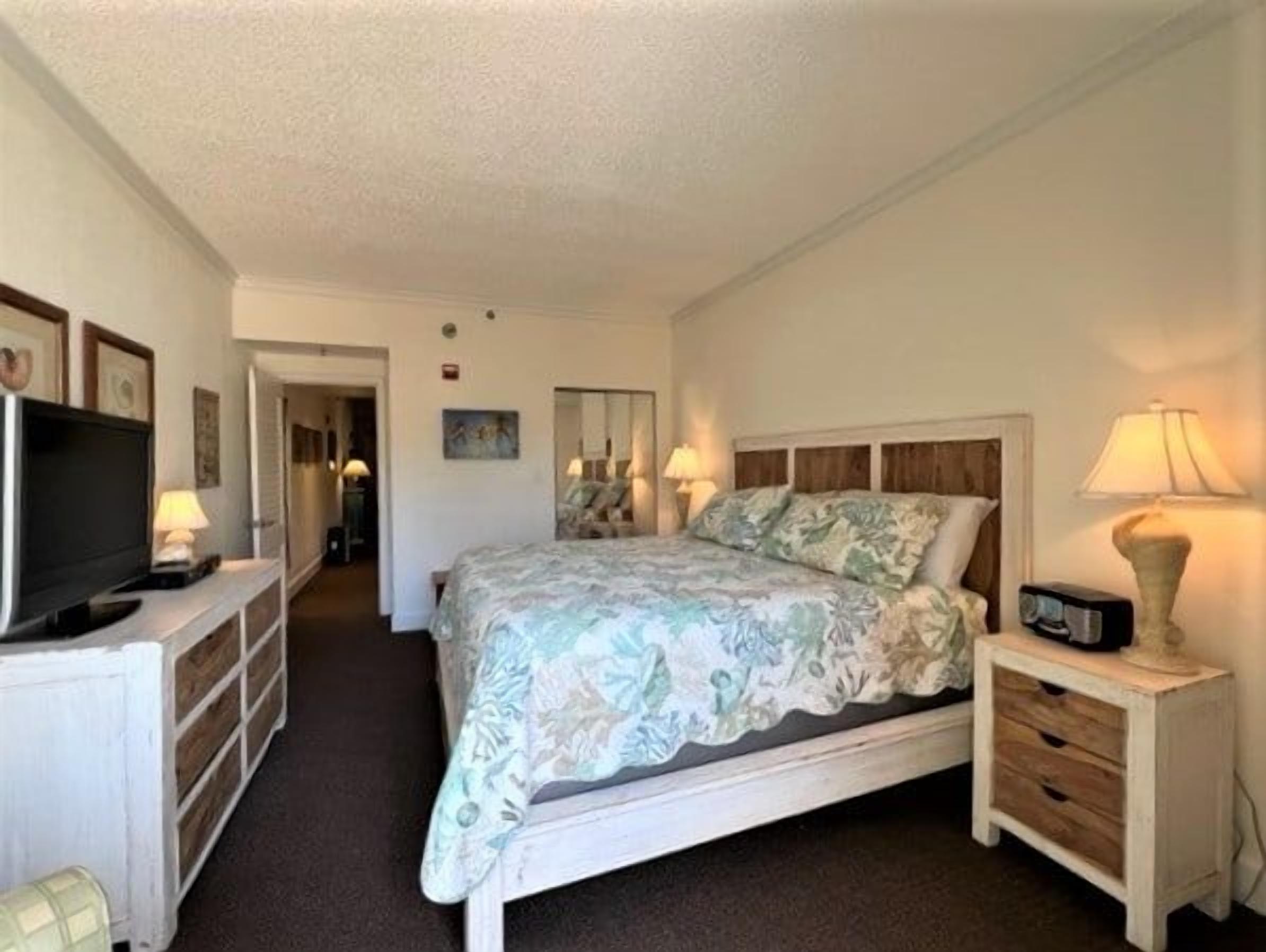 Una habitación de hotel con cama, mesitas de noche, televisor y escritorio.