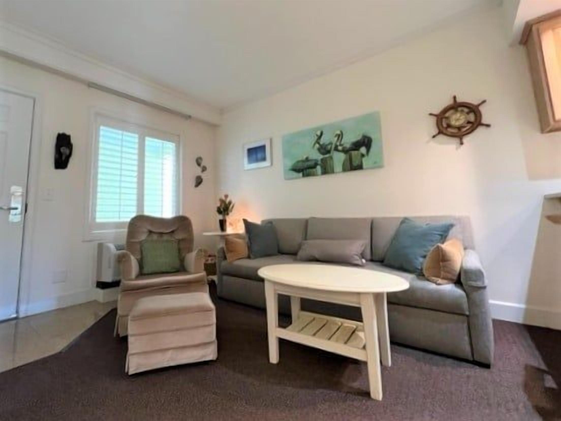 A living room with a sofa, ottoman, and a coffee table.
