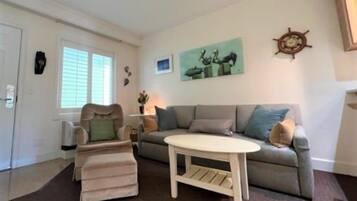 A living room with a sofa, ottoman, and a coffee table.