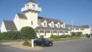 A large, multi-story building with a prominent tower and a series of dormer windows. - Just Beachy!  Short walk to the beach, shops and ferry! (Hatteras)