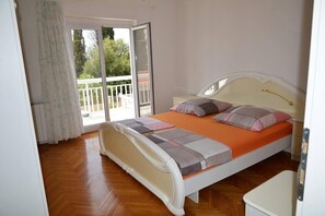 A bedroom with a bed, a nightstand, and a window with a view of a balcony. - Stunning 2-bed Apartment in Okrug Gornji (Okrug)