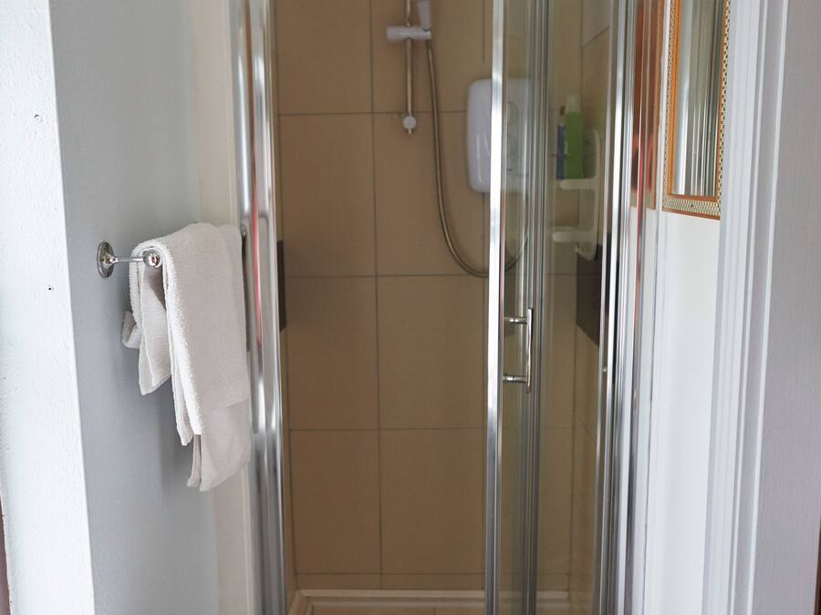 A bathroom with a glass-enclosed shower, a white sink, and a towel rack.