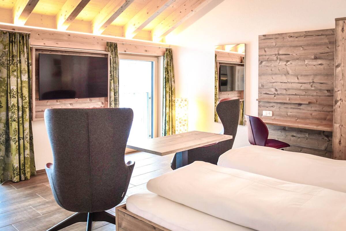 A modern hotel room with a large bed, a desk, and a TV mounted on the wall.