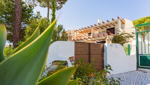 A modern house with a white exterior, a wooden gate, and a green gate. - Beach House (Golf) - Falésia/Albufeira (Olhos Dagua)