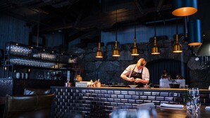 Un restaurante con mostrador de ladrillo, lámparas colgantes y una zona de bar con vasos.