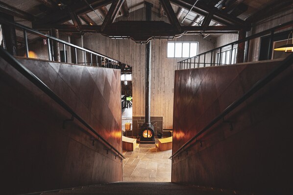 Una escalera de madera que lleva a una zona central con una chimenea.