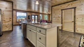 Cuina amb parets de fusta, taulell de granat i vista a les muntanyes.
