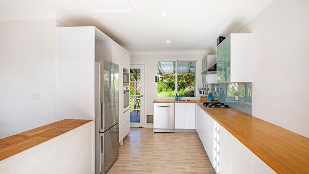 A modern kitchen with white cabinetry, stainless steel appliances, and a wooden countertop. - WindanSea Cottage - Pet Friendly - Ocean Glimpses (Vincentia)