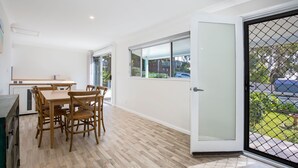 Une cuisine moderne avec des meubles blancs, une table à manger en bois et des chaises.