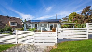 A modern house with a glass conservatory, a fenced yard, and a solar panel roof. - WindanSea Cottage - Pet Friendly - Ocean Glimpses (Vincentia)